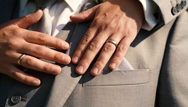 Resting hands on light-gray suit showing wedding rings and pocket square