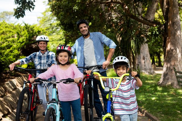 Family enjoying a sunny day in the park with their bicycles. Parents and children are smiling and wearing helmets, promoting safety and healthy lifestyle. Ideal for use in advertisements for outdoor activities, family bonding, and health and wellness campaigns.