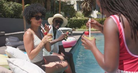 Friends enjoying poolside cocktails with colorful drinks and summer backyard leisure