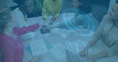 Collaborative team joining hands around table with digital hud and data visualization overlay