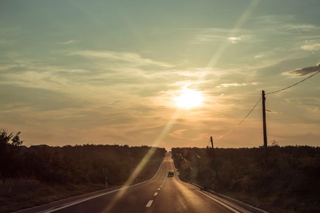 Long empty road stretching into the distance under a stunning sunset. Ideal for travel blogs, inspirational quotes, landscape artwork, and serene journey themes.