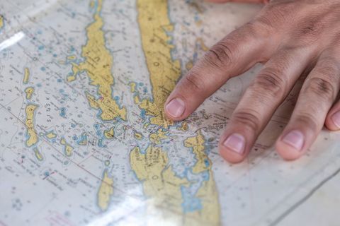 Finger pointing at nautical chart during coastal navigation and route planning