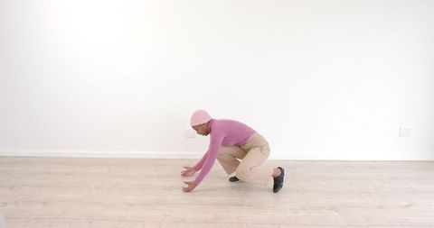 Individual in Casual Winter Outfit Reaching Forward on Hardwood Floor