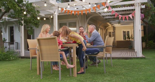 Happy caucasian parents, children and grandparents eating and talking at dinner table in garden. Summer, family, meal, celebration, togetherness and lifestyle, unaltered.