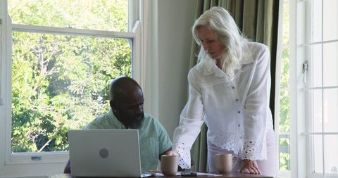 Senior Couple Planning Together Using Laptop at Sunlit Home Table