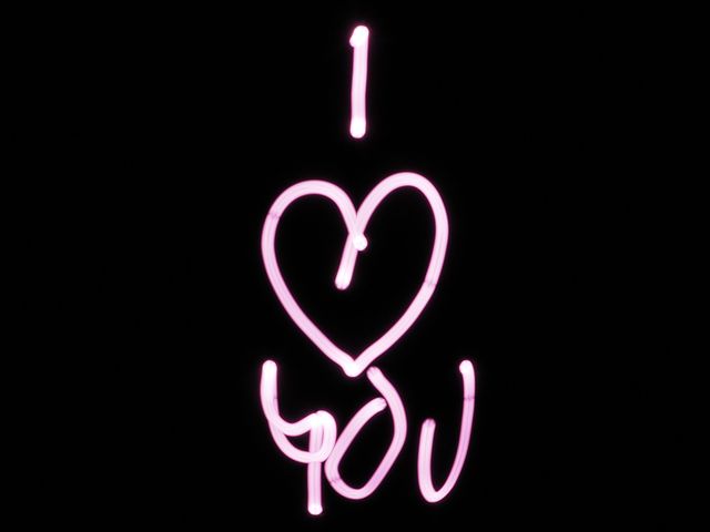 Bright pink neon 'I love you' text on black background creating a bold and romantic visual. Perfect for Valentine's Day marketing materials, greeting cards, social media posts, or romantic messages and announcements. It highlights love and affection, setting a passionate tone.