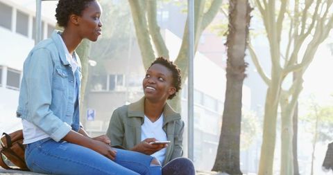 Twin Sisters Enjoying Outdoor Conversation with Smartphone