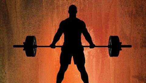 Silhouette weightlifter holding loaded barbell against orange grunge backdrop