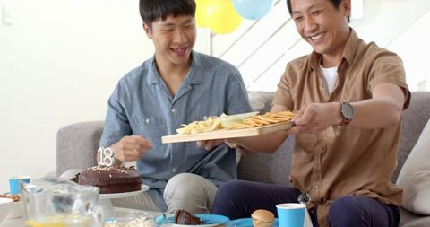 Father and Son Celebrating Together at Home Enjoying Snacks