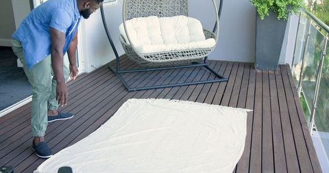 Man Arranging Blanket on Modern Balcony for Relaxation