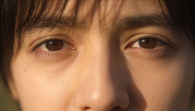 Sunlit closeup of woman's brown eyes and skin texture at golden hour