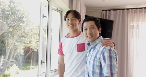 Asian Father and Son Bonding by Window with Garden View