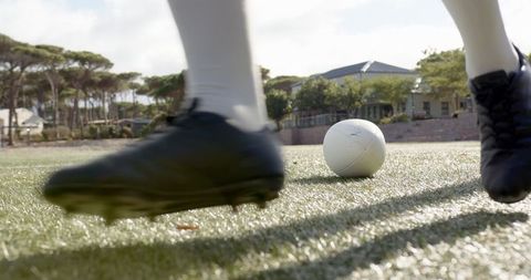 Athlete approaching soccer ball with black cleats on turf field