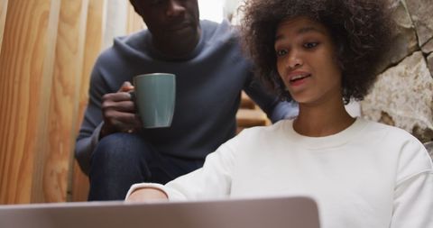 Mixed Race Duo Collaborating on Laptop at Home on Stairs