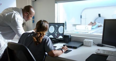 African american doctor and technologist reviewing brain mri during patient scan