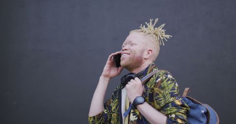 Smiling albino african american man talking on smartphone outdoors