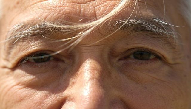 Close-up senior male eyes showing detailed wrinkles and skin texture for aging and wisdom