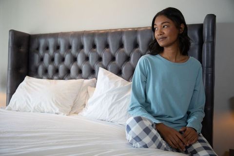 Young Woman in Cozy Pajamas Relaxing on Bed in Modern Bedroom