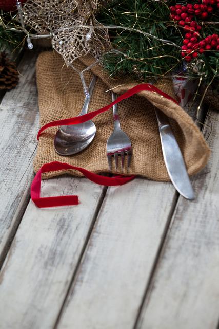 Cutlery with sack and christmas decoration on a plank