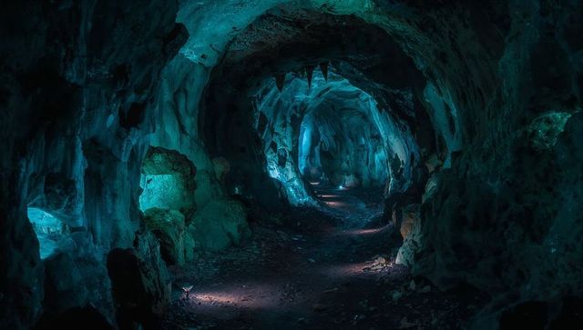 Mysterious cave passage lit by ethereal blue-green glow