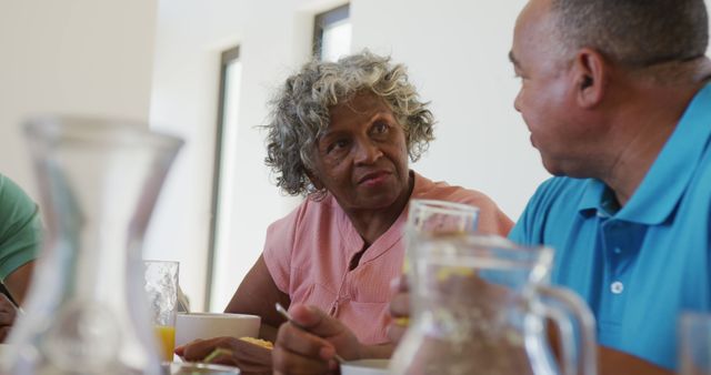 Senior woman engaged in conversation with middle-aged man at dining table - Download Free Stock Images Pikwizard.com