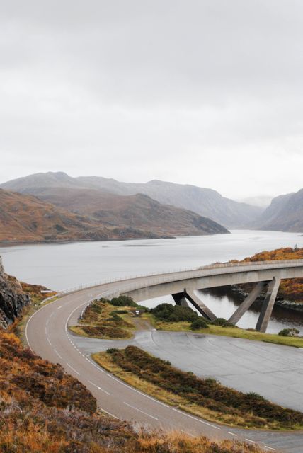 Winding Mountain Road Leading to Modern Bridge Over Serene Lake - Download Free Stock Images Pikwizard.com