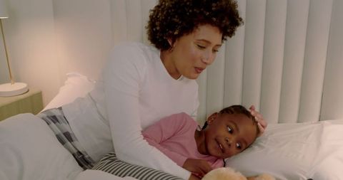 Mother Cuddling Daughter in Pajamas at Bedtime