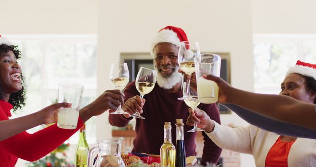 Happy family celebrating Christmas with a toast, wearing Santa hats - Download Free Stock Images Pikwizard.com