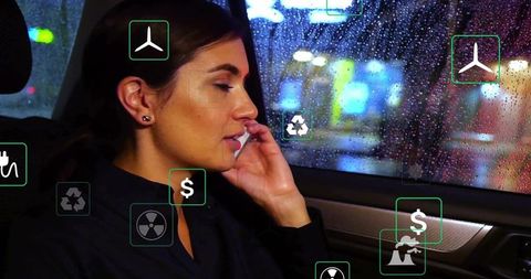 Businesswoman using smartphone with augmented reality icons in rainy car at night