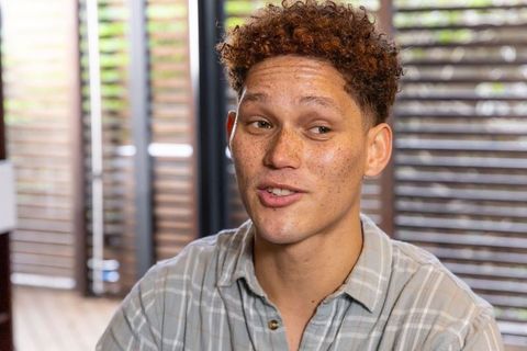 Smiling man in plaid shirt relaxing by wooden blinds