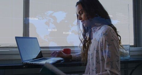 Remote professional working on laptop at bright windowsill with world map data overlay