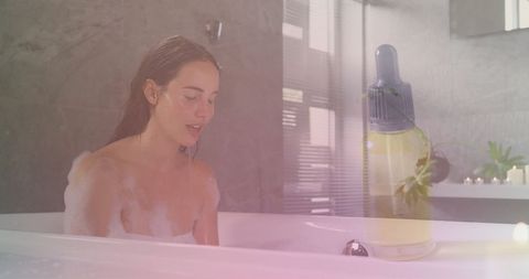 Woman relaxing in bubble bath with essential oils for self-care
