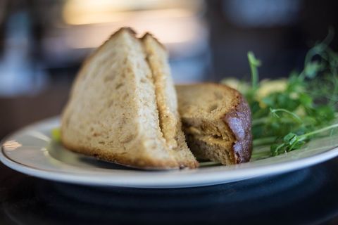 Serving creamy peanut butter sandwich on whole wheat bread with fresh pea shoots