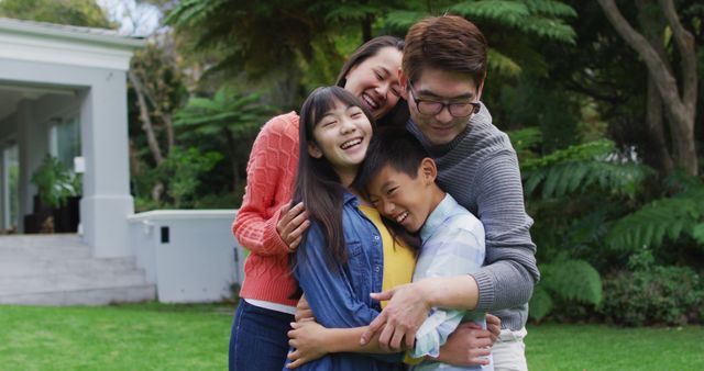 Smiling asian parents hugging happy son and daughter in garden. happy family, at home in isolation during quarantine lockdown.