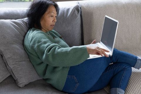 Senior Woman Using Laptop on Comfortable Sofa at Home