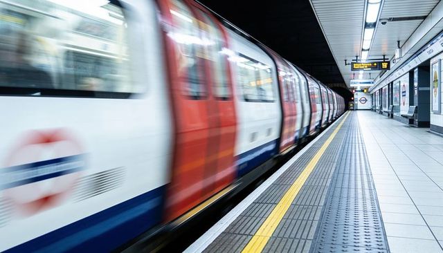 London tube train blurring past empty platform showing yellow safety line