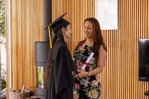 Asian mother celebrating daughter's graduation near modern stove