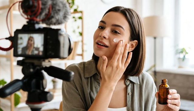 Applying facial serum on camera creating skincare tutorial in bright home studio