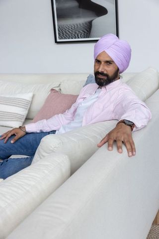 Indian man relaxing on modern sofa in minimalist living room