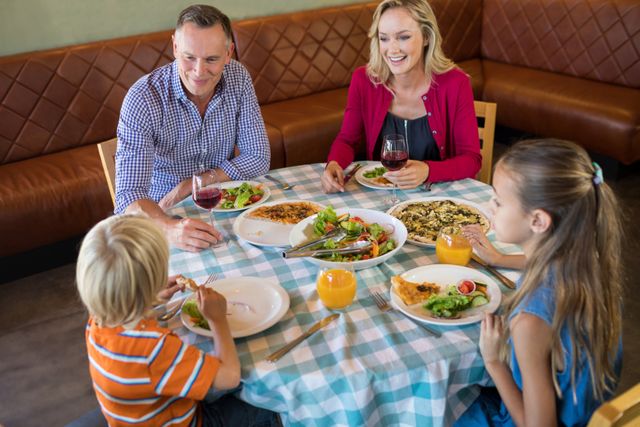 High angle view of happy family talking while dining at restauranrt
