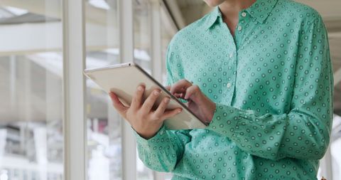 Woman in Green Shirt Using Tablet in Modern Office Environment