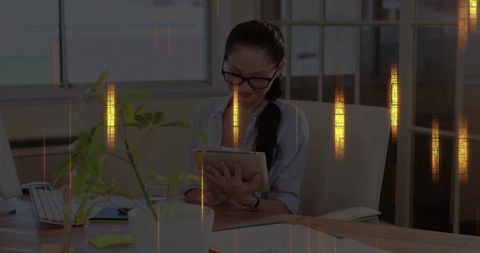 Businesswoman using tablet smiling as golden light streaks drift across open-plan office