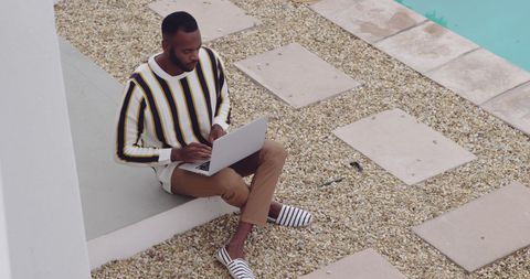 Focused Man Using Laptop Beside Pool