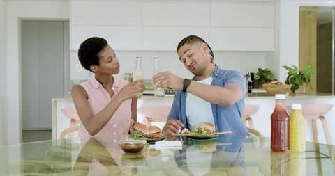Diverse Couple Enjoying Burger Meal in Contemporary Home Kitchen