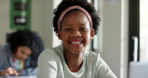 Smiling African American Girl Studying at Classroom Desk with Laptop and Headband