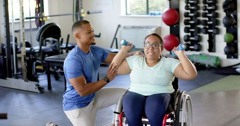Physical Therapist Assisting Woman in Wheelchair with Exercise Dumbbells