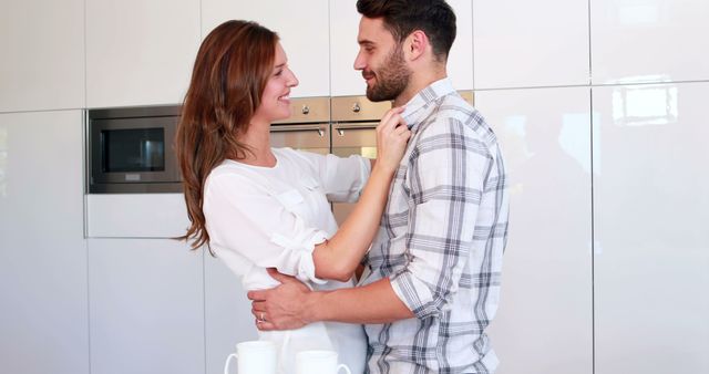 Happy couple embracing and holding cups in kitchen