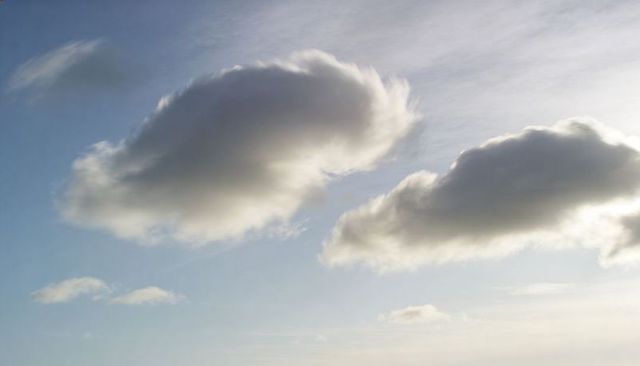 Drifting dome-shaped clouds casting soft shadows over pale blue sky