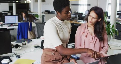 Focused Businesswomen Collaborating on Laptop in Modern Office