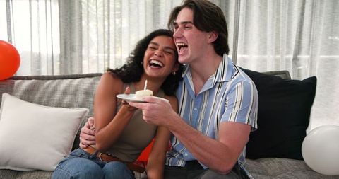 Joyful Multiracial Couple Celebrating Birthday on Sofa